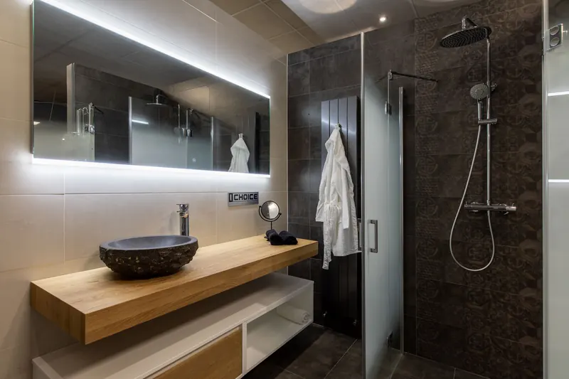 Badkamer met een stenen waskom op een houten blad en een inloopdouche