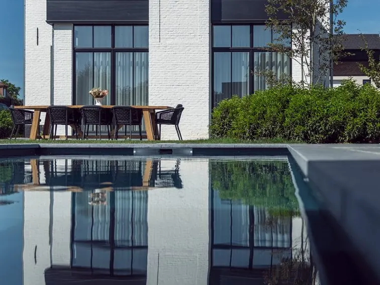 Zwembad met natuursteen zwembadranden in een moderne tuin